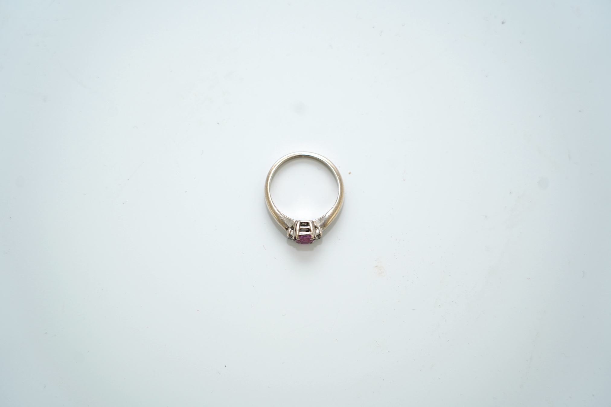 A modern 18ct white gold, single stone pink sapphire and two stone diamond set ring, size J, gross weight 3.7 gram. Condition - good